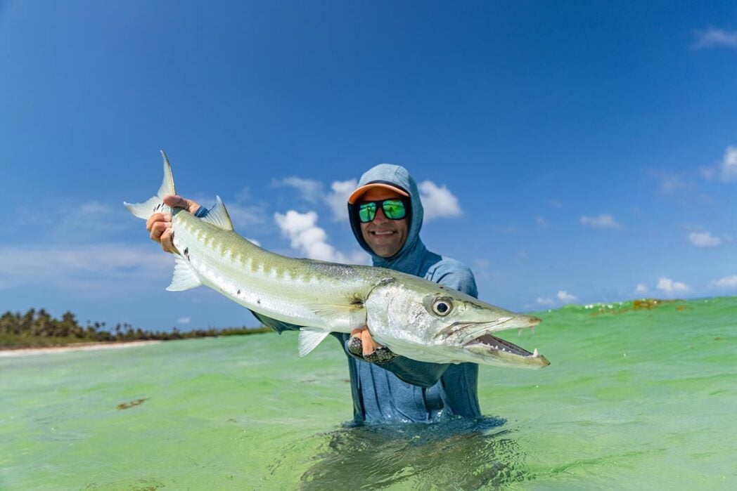 Angler in sea holding barracuda