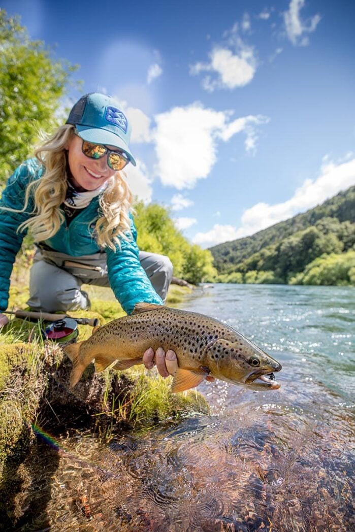 Woman returning wild river trout, Chile