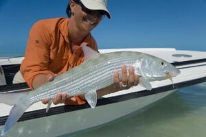 Woman angler holding large bonefish caught fly fishing Bahamas