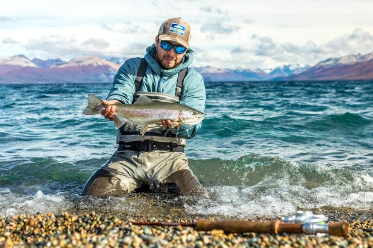 Angler holding rainbow fish in lake, Patagonia