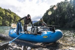 Fly fishing from a raft on a forested river in Southern Patagonia