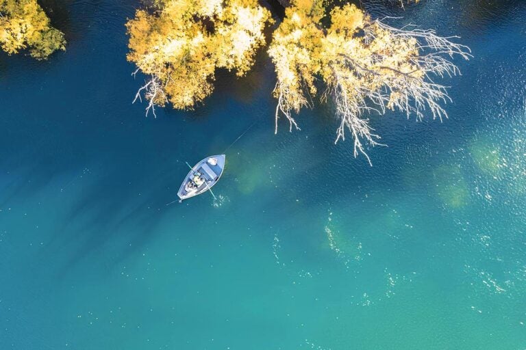 Aerial shot of drift boat with anglers floating down turquoise waters in Patagonia, Argentina