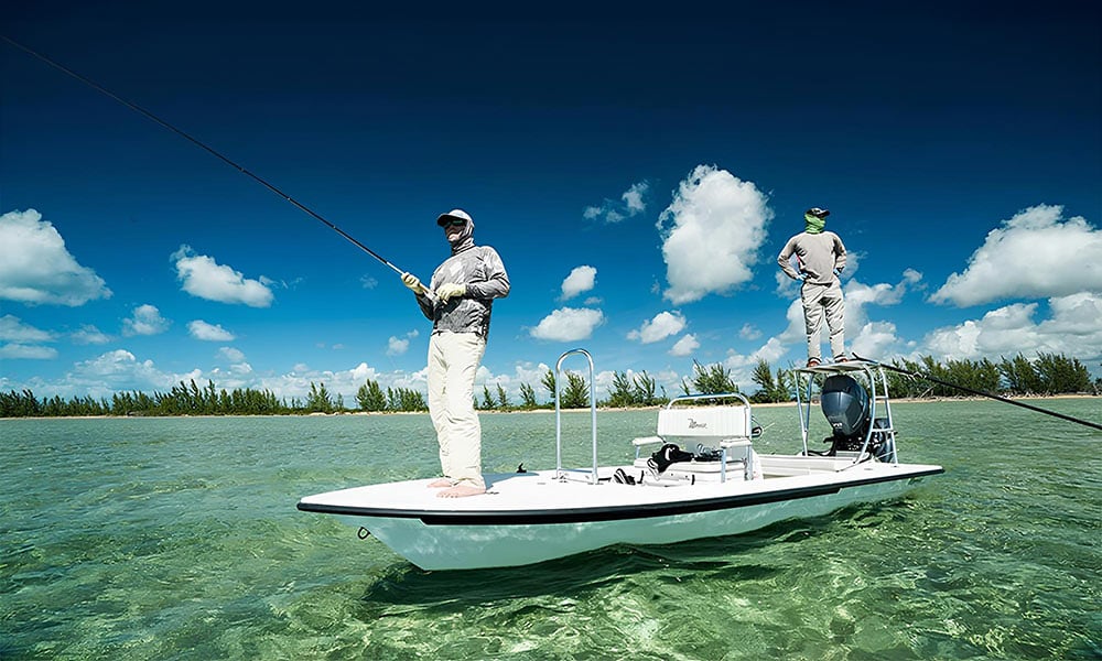 Fly fisherman standing on deck of skiff boat in shallow tropical waters