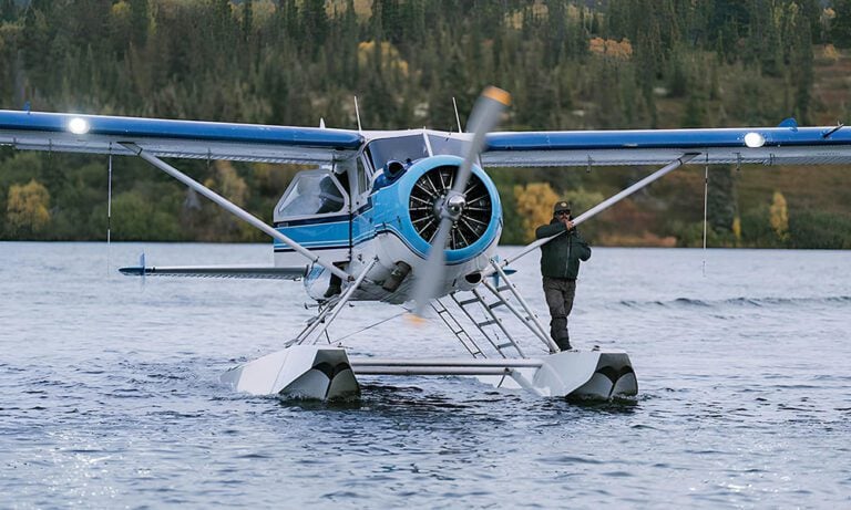 Floatplane in Alaska on lake with pilot standing on the float