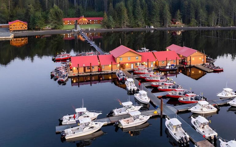 QCL Queen Charlotte fishing lodge in Haida Gwaii. Aerial view of lodges and fleet of boats surrounded by water.