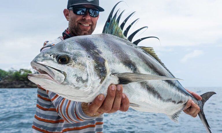 Angler holding roosterfish caught fishing off coast of Colombia on the fly