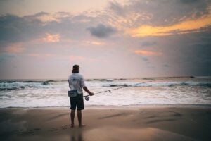 Saltwater fly fisherman standing on beach at dusk in Africa