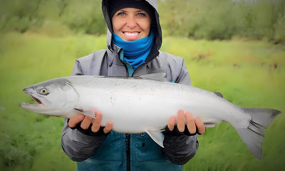 Silver coho salmon held by woman fly fisher