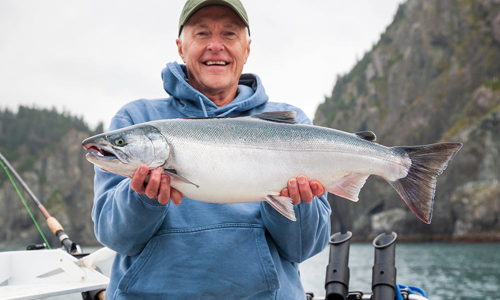 Silver coho salmon caught trolling held by boat fisherman