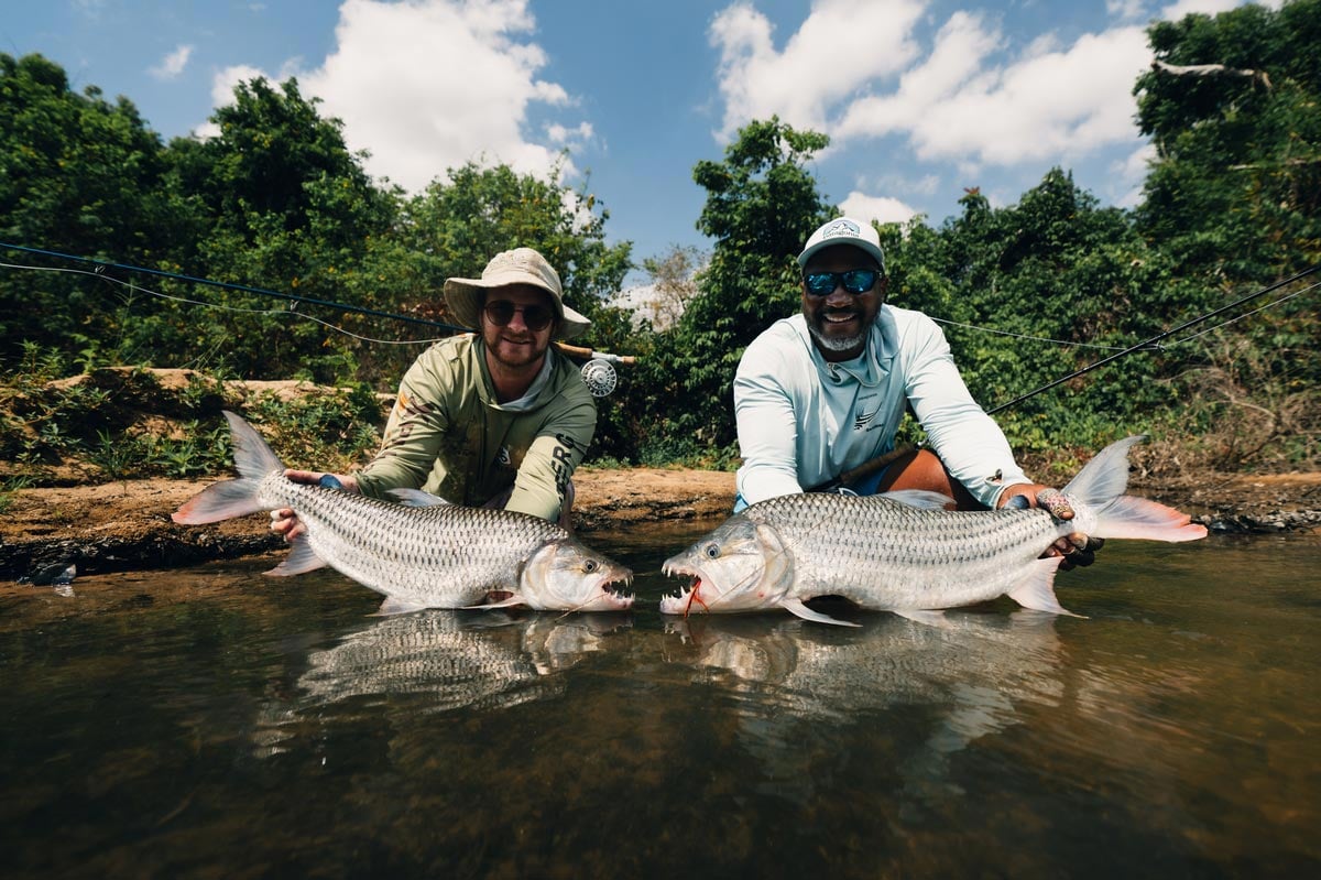 Two anglers posing for photo whilst each holding a tigerfish