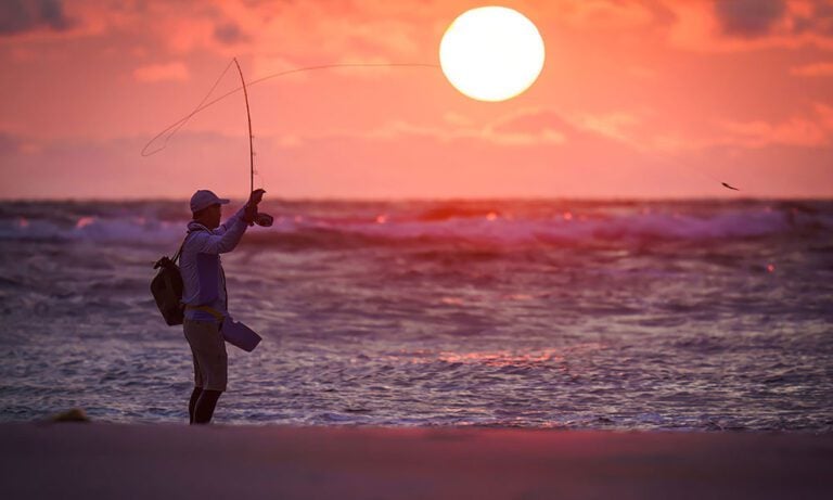 Saltwater fly fisherman casting into sunset on Gabon coastline in Africa