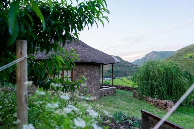 Lesotho fishing camp with traditional stone rondavel and mountains in background