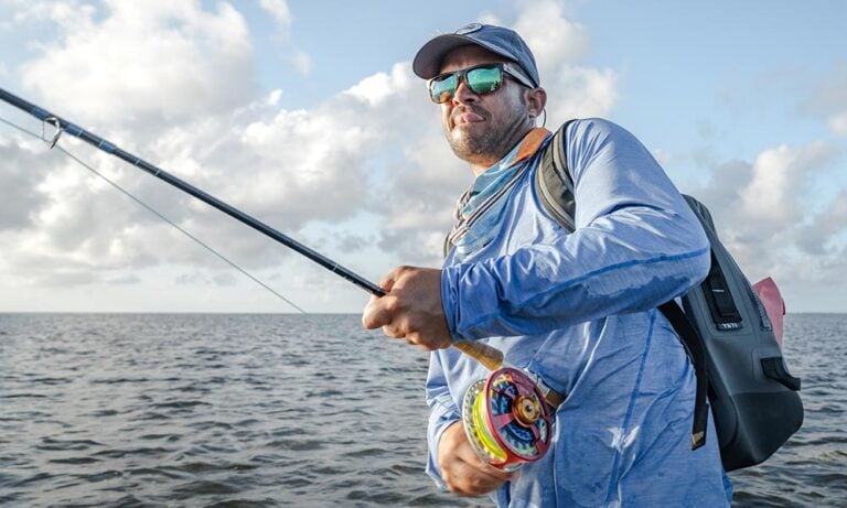 Angler fly fishing in saltwater with large arbor reel, casting in the ocean