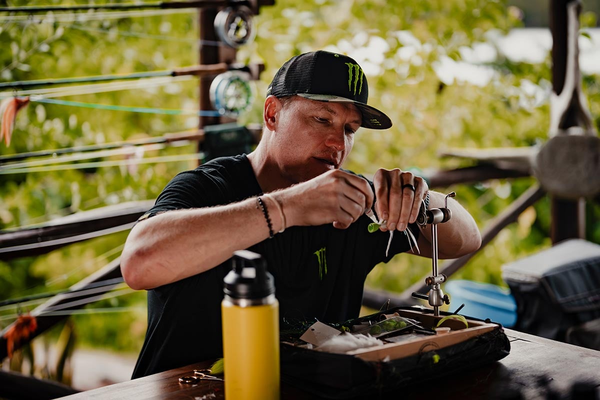 Man tying fishing flies at camp in West Africa