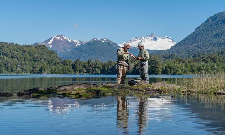 Fly fishermen by lake in Rio Negro Argentina, with snow capped mountain in background