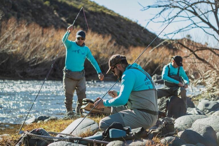 Fishing guides in Patagonia setting up fly rods beside trout river