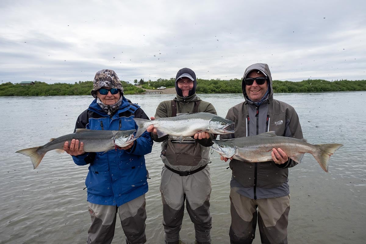 Angler group in Alaska holding coho salmon caught on river