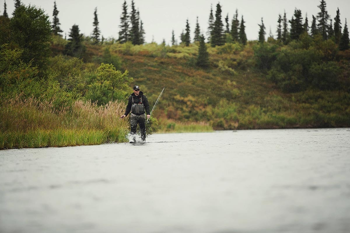 Angler in Alaska walking with rod beside river