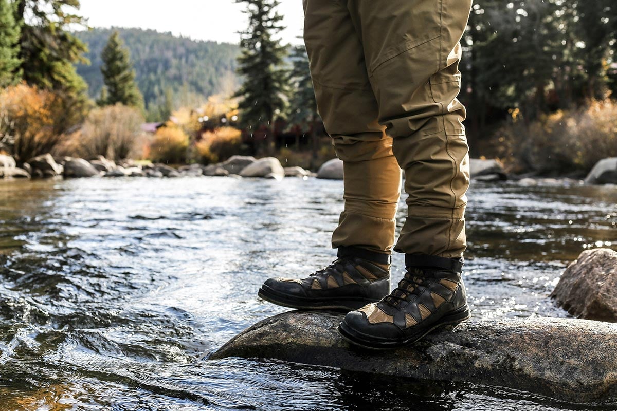 River angler wearing wading boots with rubber soles standing on rock with water flowing around it