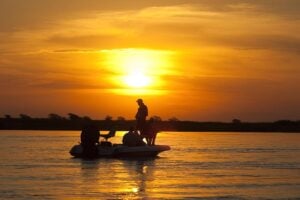 Silhouette of anglers fishing from a boat at sunset on the upper Zambezi, Shackletons Lodge, Zambia